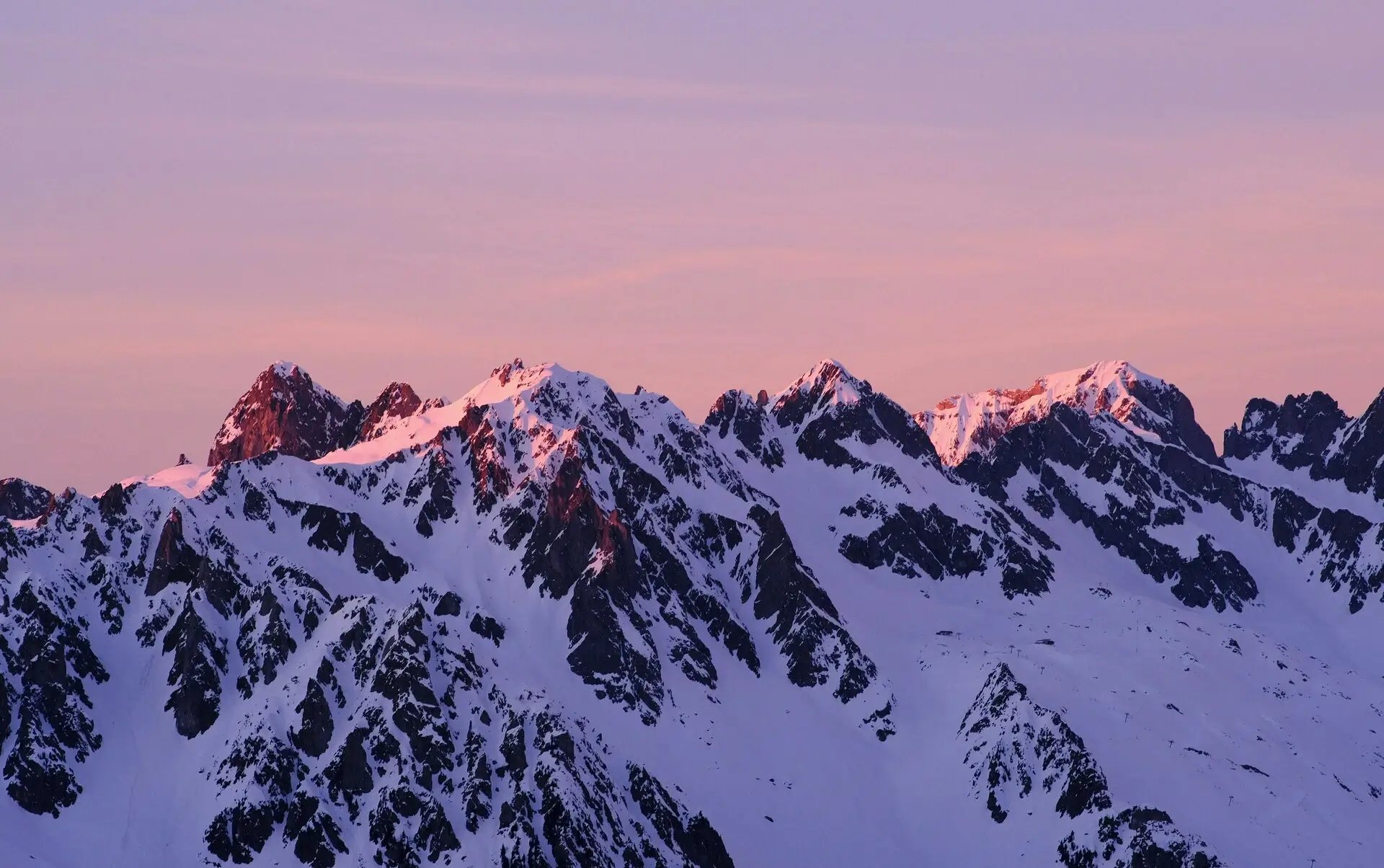 Bergkette mit viel Schnee in lila Sonnenlicht